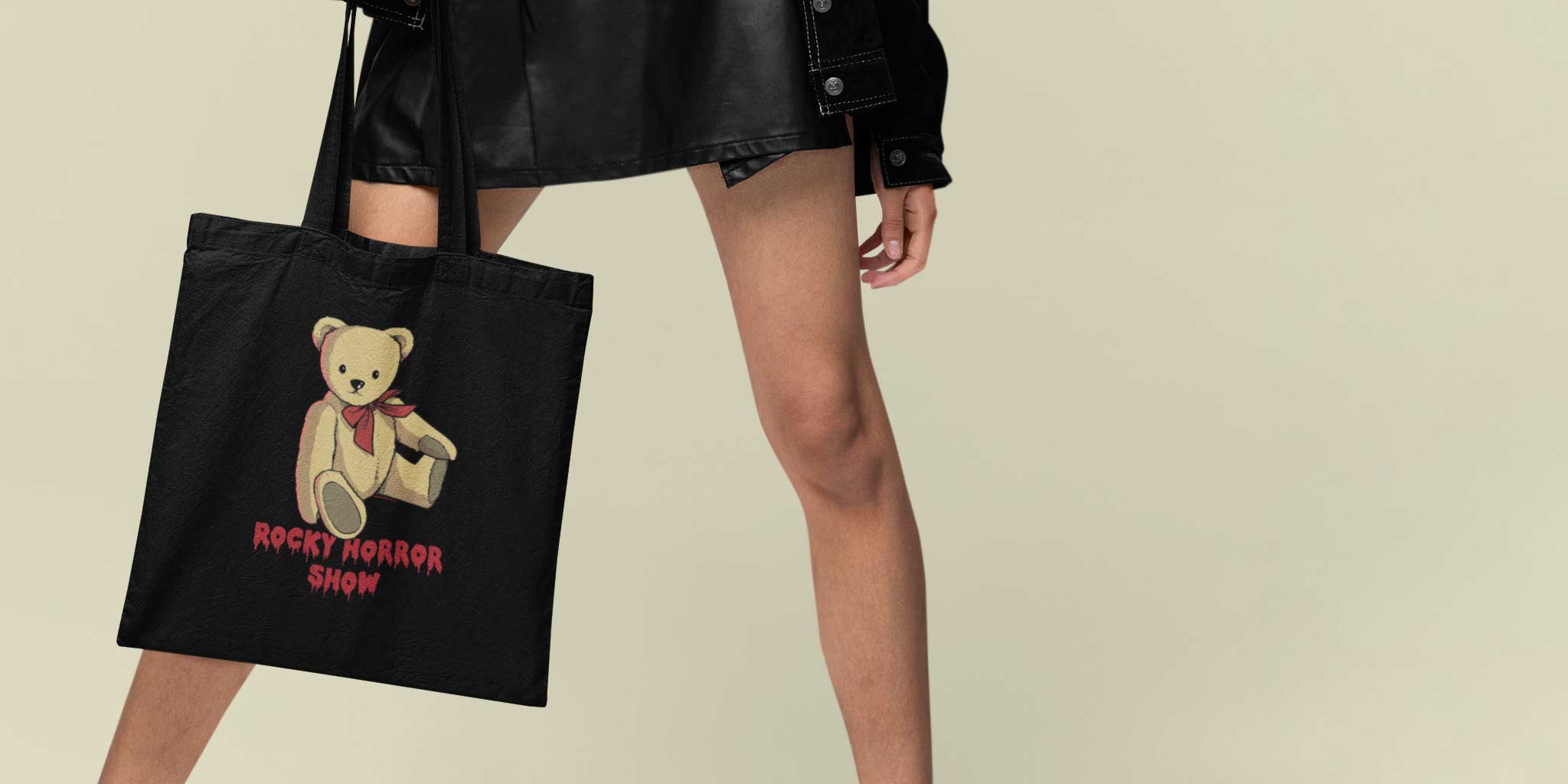 A young woman holding an official Rocky Horror Eddie's Teddy Tote Bag